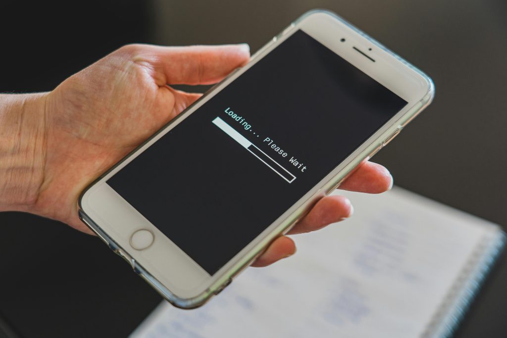 Close-up of a hand holding a smartphone with a loading screen displayed, showcasing technology usage.